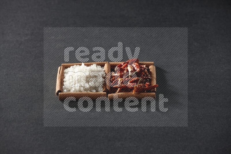 2 squares of cinnamon sticks full of chilis and salt on black flooring