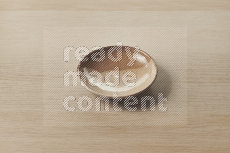 A multicolored pottery plate on light wooden background