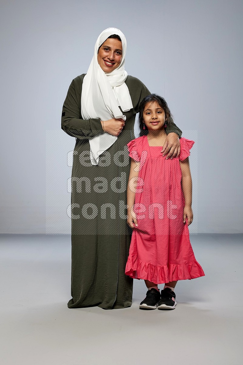 A girl and her mother interacting with the camera on gray background