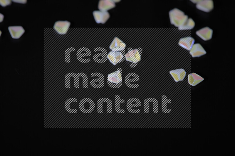 Colorful plastic shards for decoration scattered on a black background
