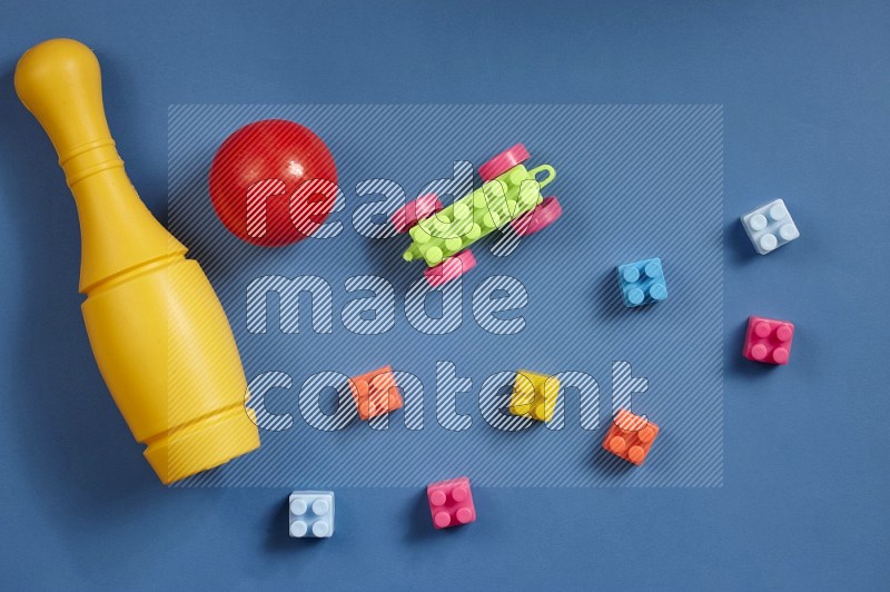 Plastic building blocks, balls and bowling pins on blue background in top view (kids toys)