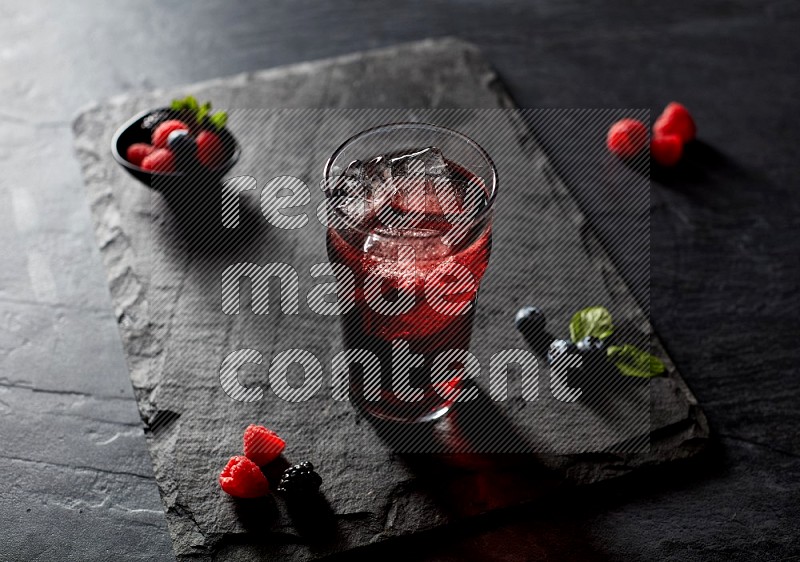 A glass of mixed berries juice on black background