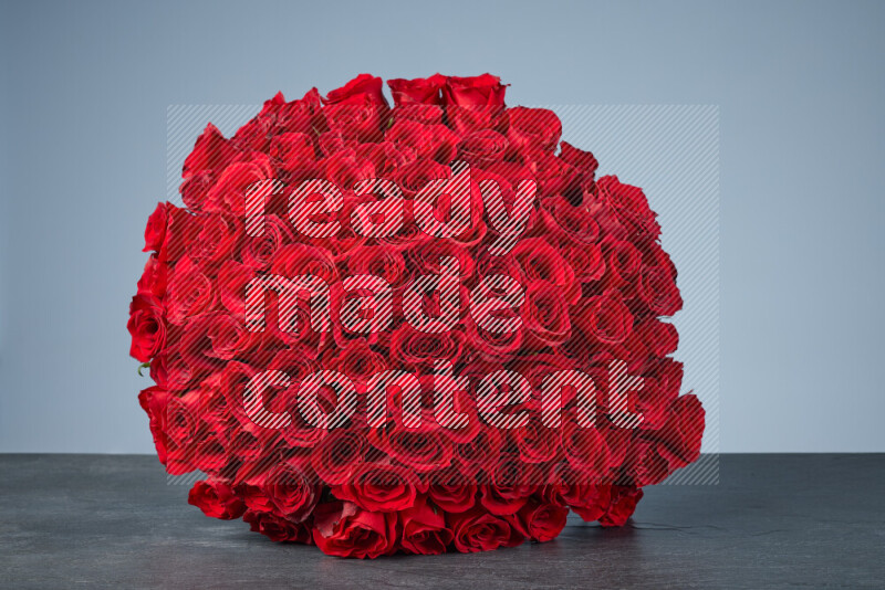 A sphere of vibrant red roses arranged tightly on black marble background
