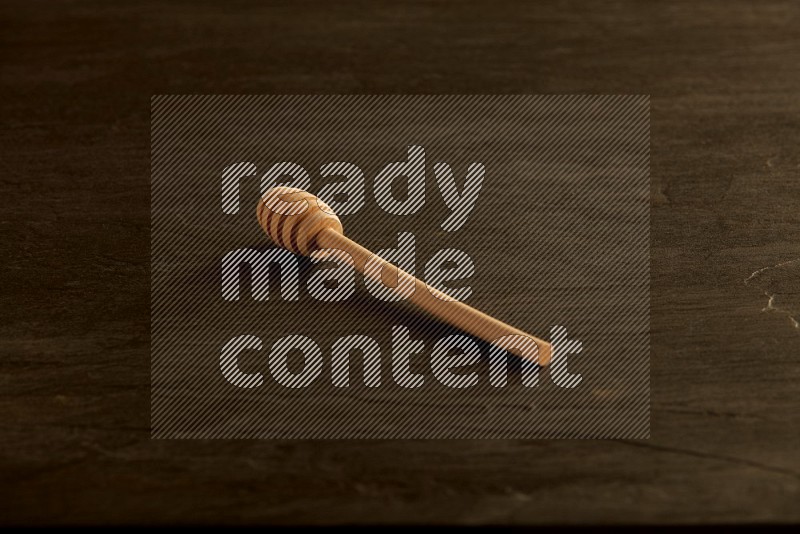 Wooden honey dipper on black slate background