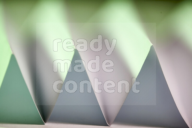 صورة مجردة مقربة تظهر طيات ورقية هندسية حادة بتدرجات اللون الأبيض و الأخضر