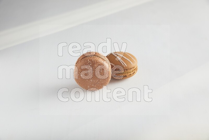 45º Shot of of two assorted Brown Irish Cream, and Brown Hazelnuts macarons on white background