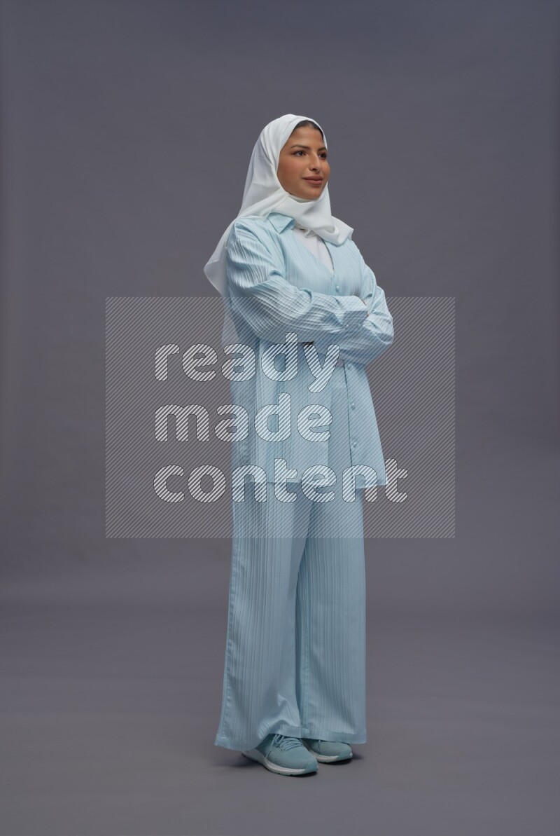 Saudi woman wearing hijab clothes standing with crossed arms on gray background