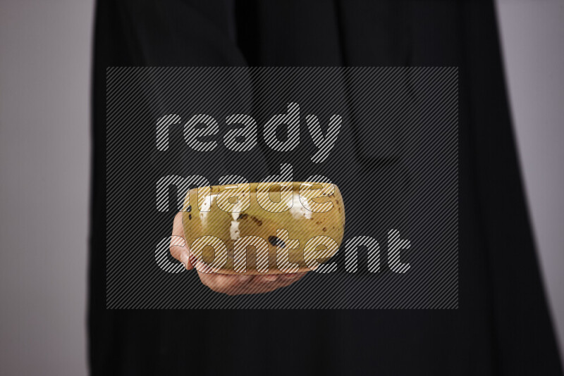 A woman in black abaya holding different pottery essentials in different positions