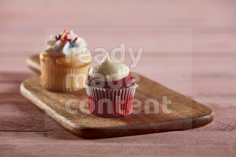 Red velvet mini cupcake topped with cream on a wooden board
