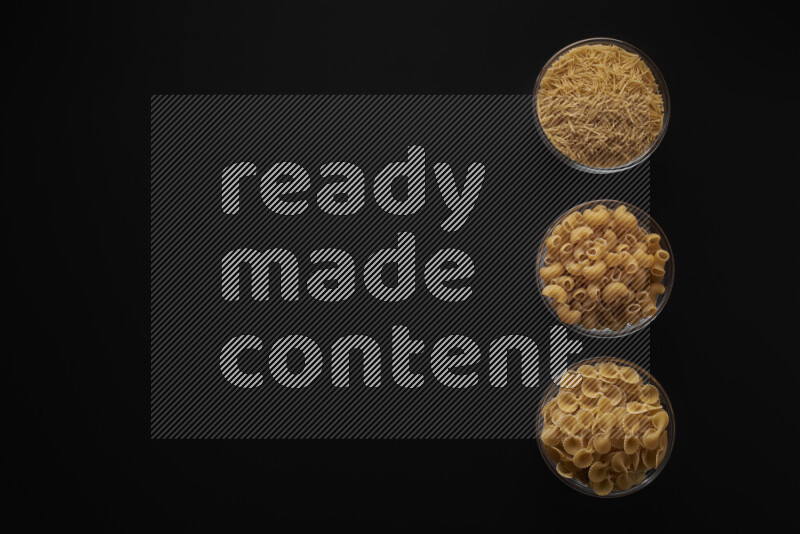 Different pasta types in 3 glass bowls on black background