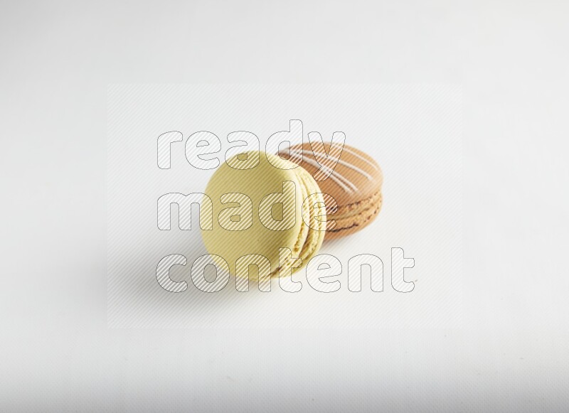45º Shot of of two assorted Brown Irish Cream, and Yellow Lime macarons on white background