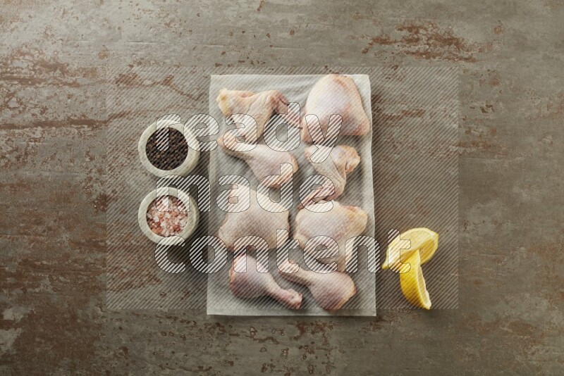 Mixed fresh chicken pieces on a parchment paper direct on a textured rustic background