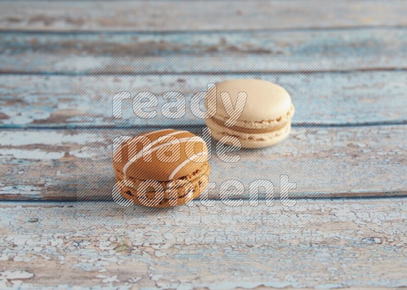 45º Shot of of two assorted Brown Irish Cream, and White Caramel fleur de sel macarons on light blue background