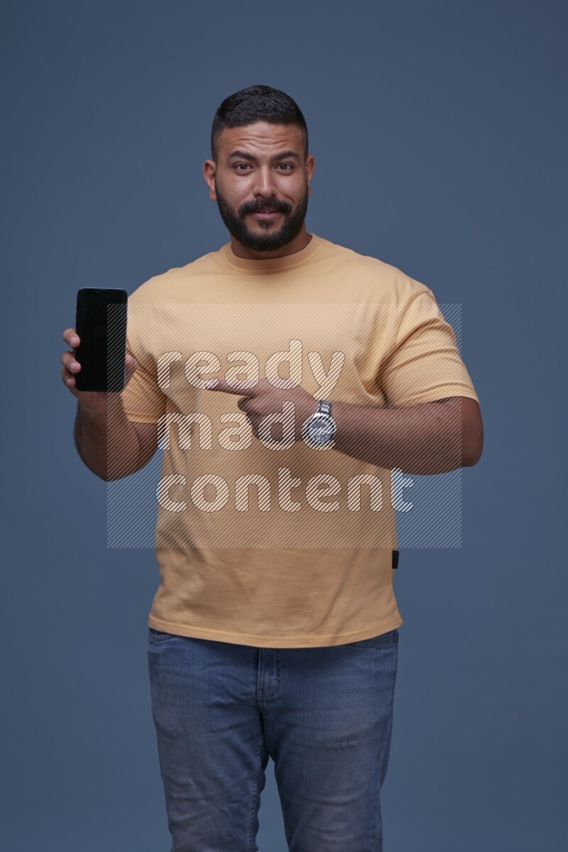 A man Pointing at a Smartphone on Blue Background wearing Orange T-shirt