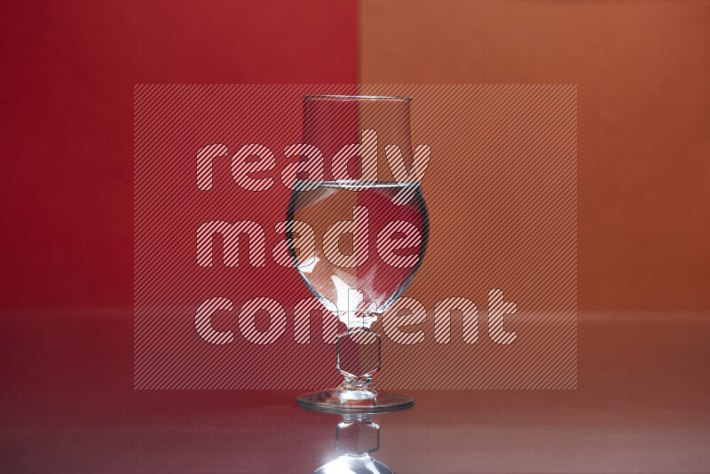 The image features a clear glassware filled with water, set against red and dark orange background