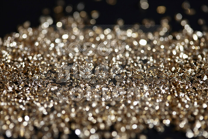 Gold shimmering fragments of glass scattered on a black background