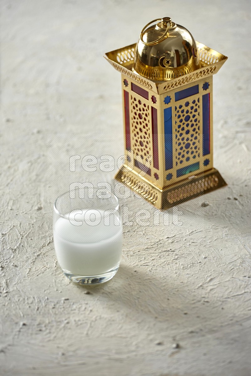 A golden lantern with different drinks, dates, nuts, prayer beads and quran on textured white background