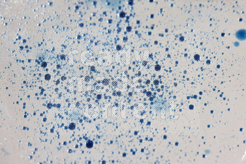 Close-ups of abstract blue watercolor drops on oil Surface on white background