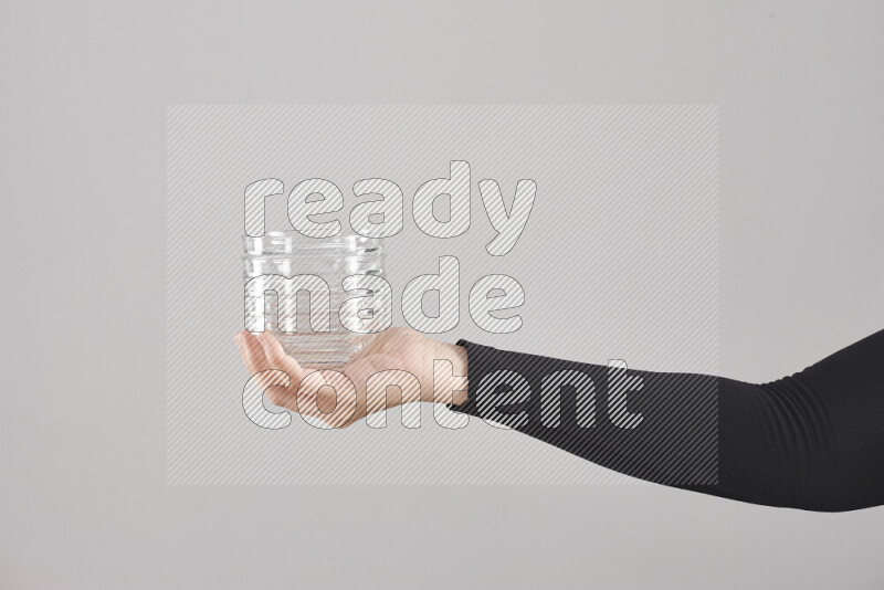 A woman in black abaya holding different glassware in different positions