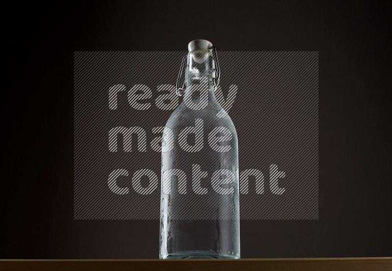 Low angle shot of a bottle of water and ice on grey background