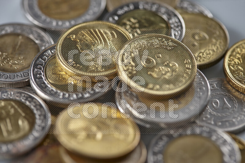 A close-up of scattered mixed Egyptian coins such as One pound, 50 and 25 piasters on grey background