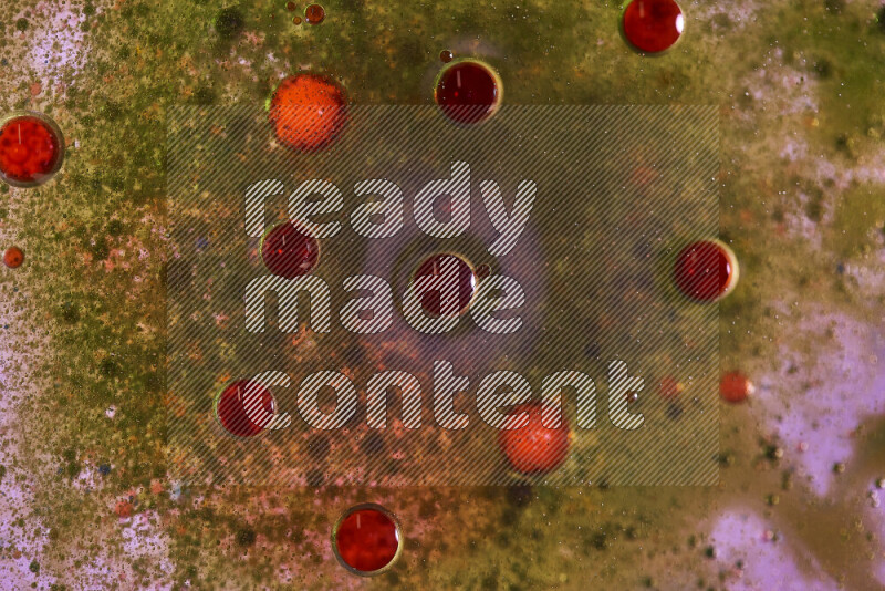 Close-ups of abstract green and red watercolor drops on oil Surface on pink background
