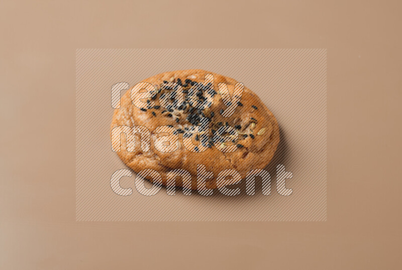 a whole Hasawi cookie with grains on a brown background