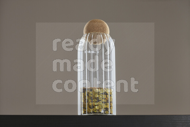 Sequins in a glass jar on black background