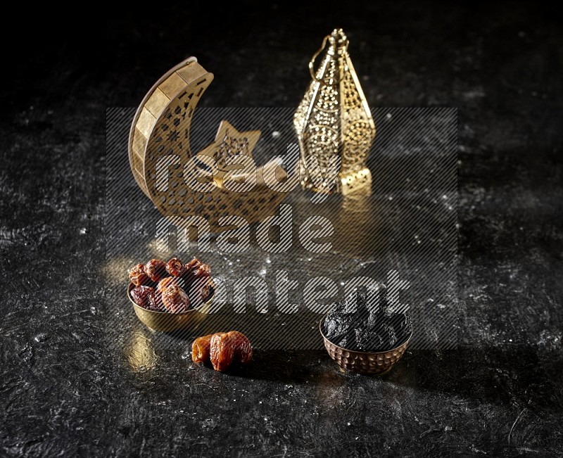 Dates in a metal bowl with dried plums beside golden lanterns in a dark setup