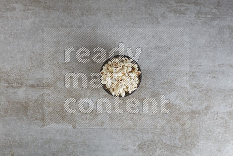 popcorn in multi-colored pottery bowl on a grey textured countertop
