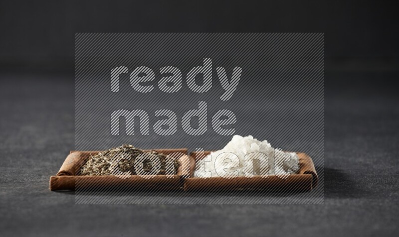 2 squares of cinnamon sticks full of white salt and cumin on black flooring