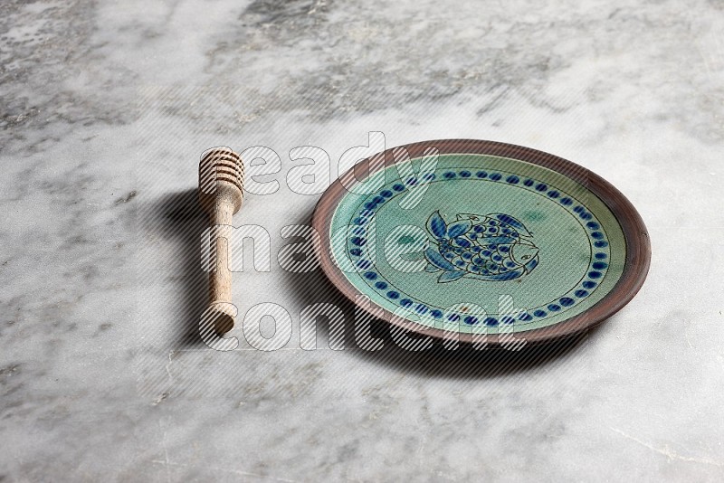 Decorative Pottery Plate with wooden honey handle on the side with grey marble flooring, 45 degree angle
