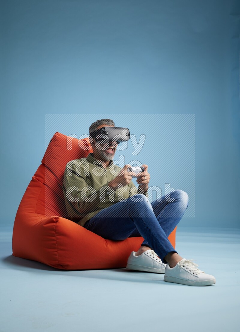 A man sitting on an orange beanbag and gaming with VR