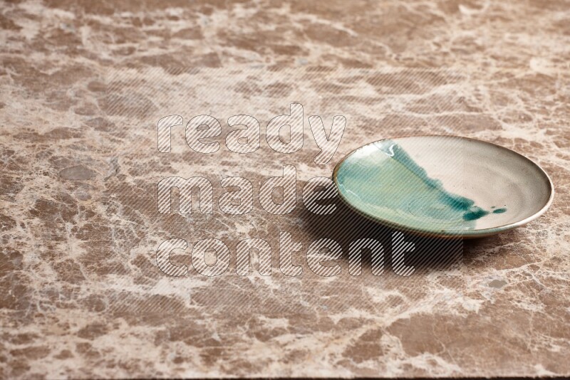 A multicolored pottery plate on beige marble background