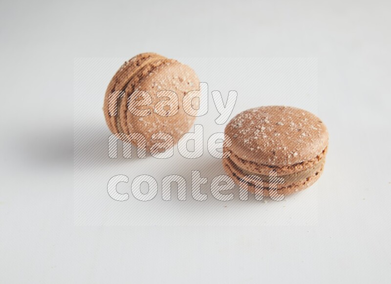45º Shot of two Brown Hazelnuts macarons on white background