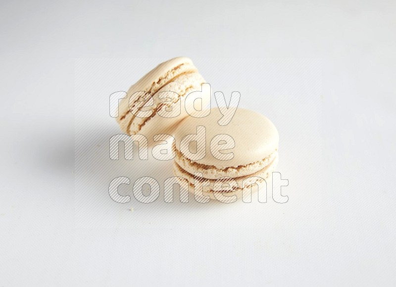 45º Shot of two White Caramel fleur de sel macarons on white background