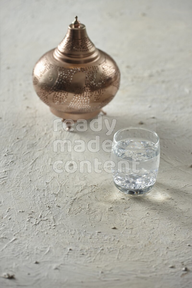 A golden lantern with different drinks, dates, nuts, prayer beads and quran on textured white background