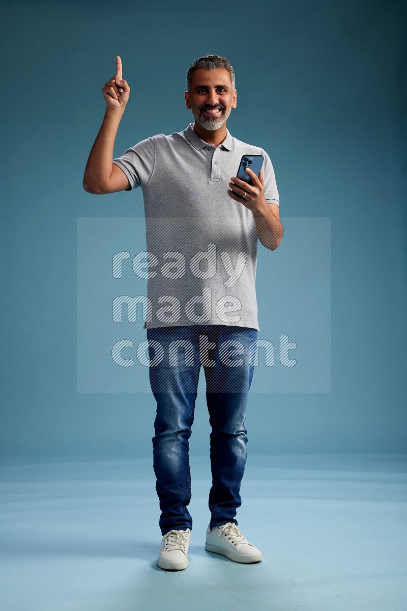 Man Standing texting on phone on blue background