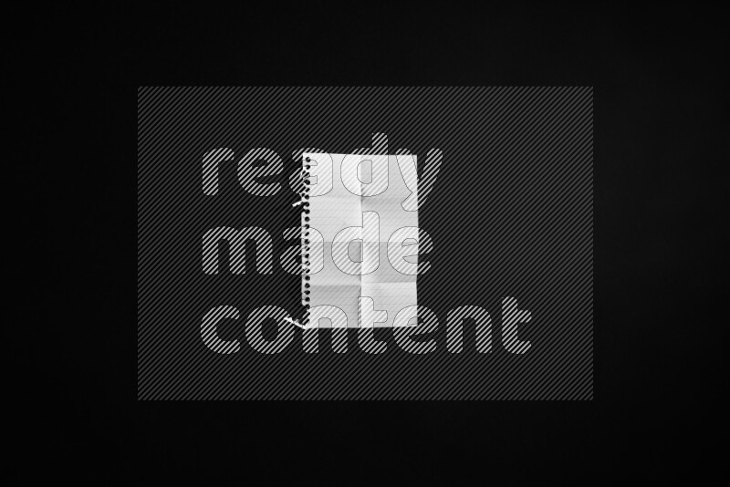 Folded notebook sheet on black background