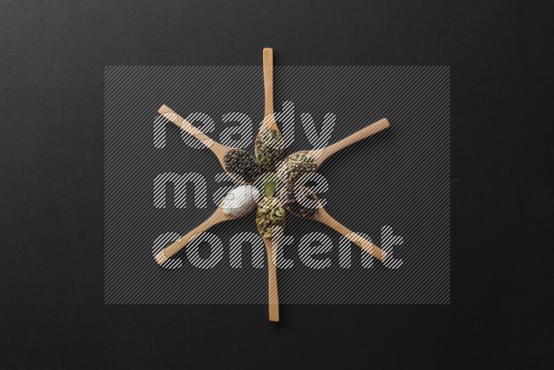 wooden spoons filled with white peppers, cloves, cardamom, salt, black peppers and basil on black flooring and shaped like a clock