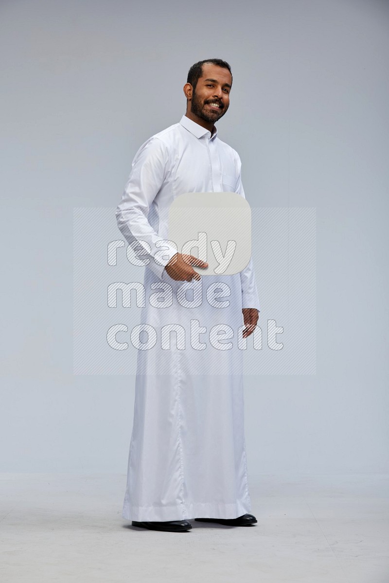 Saudi man wearing Thob standing holding social media sign on Gray background