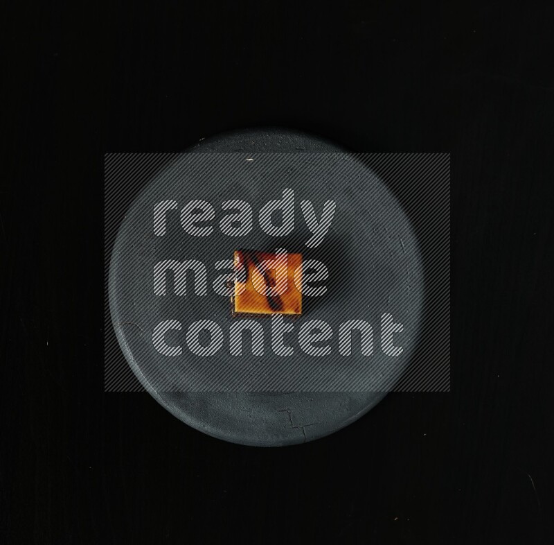 Assorted desserts in a black pottery plate on black background