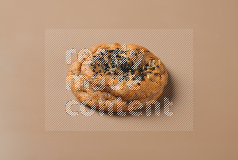 a whole Hasawi cookie with grains on a brown background