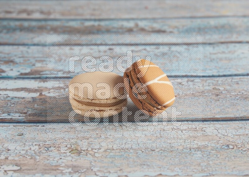 45º Shot of of two assorted Brown Irish Cream, and White Caramel fleur de sel macarons on light blue background