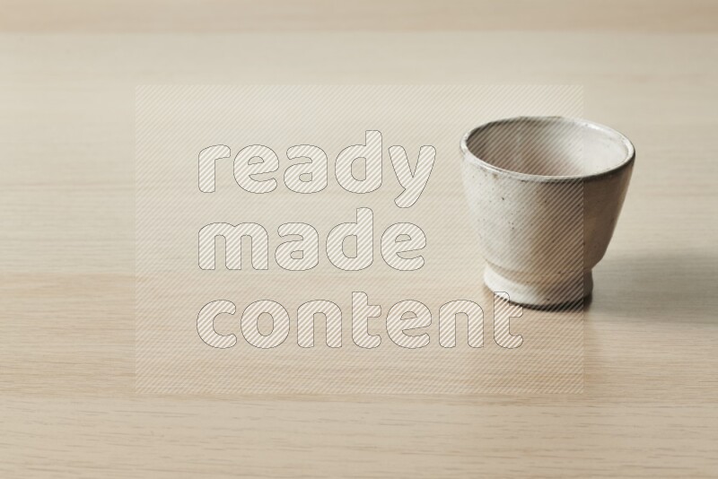 A pottery cup on light wooden background
