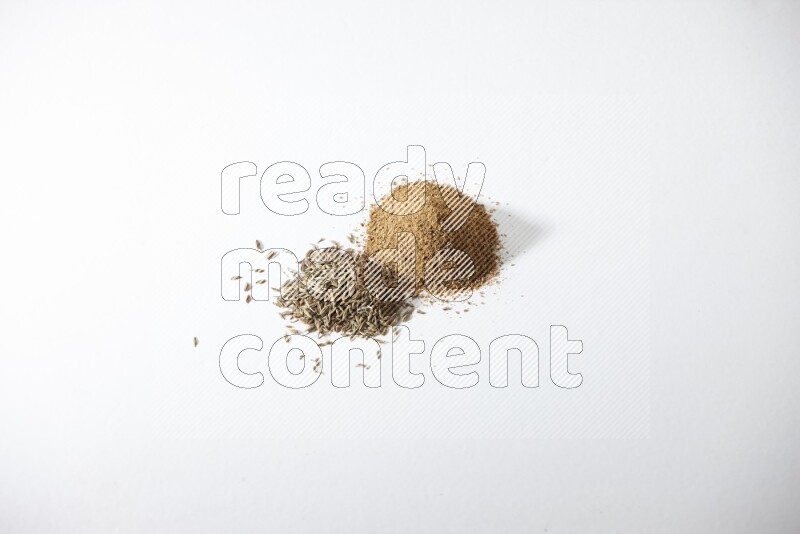Cumin seeds and cumin powder on white flooring
