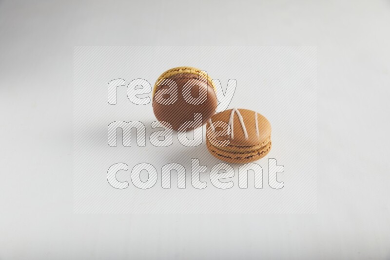 45º Shot of of two assorted Brown Irish Cream, and Yellow, and Brown Chai Latte macarons on white background