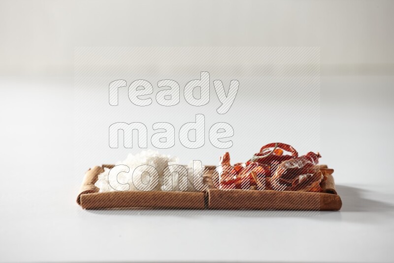 مربعان من أعواد القرفة ممتلئان بالفلفل الحار المجفف والملح الأبيض علي خلفية بيضاء