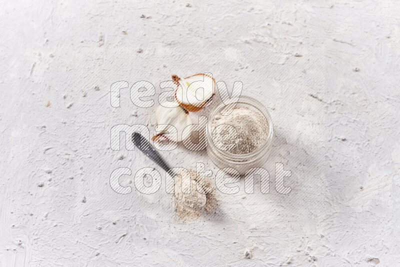 A glass jar full of onion powder on white background