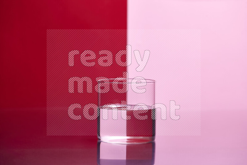 The image features a clear glassware filled with water, set against red and rose background